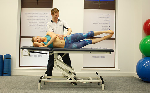 Pilates instructor assisting a client on an exercise bed Pilates instructor assisting a client on an exercise bed