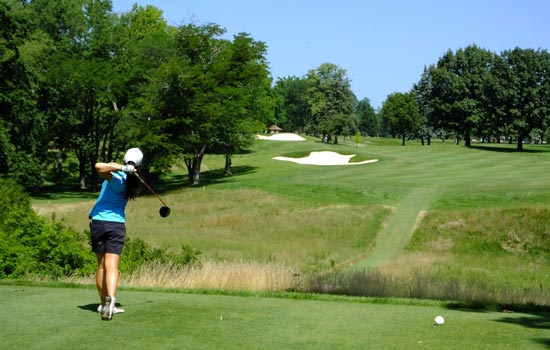 A man taking the opening shot in a game of golf.