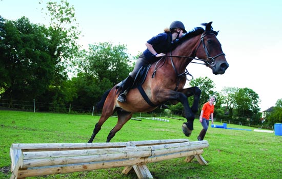 Women riding a horse in an open feild.